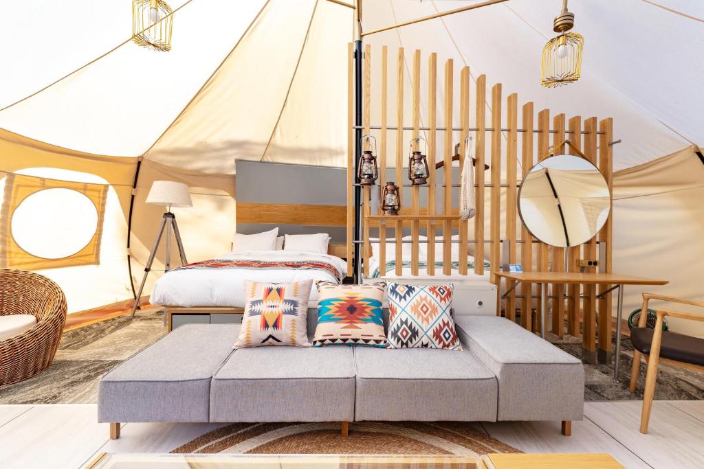 ein Schlafzimmer in einem Zelt mit einem Bett und Kissen in der Unterkunft fabula glamping in Kimitsu