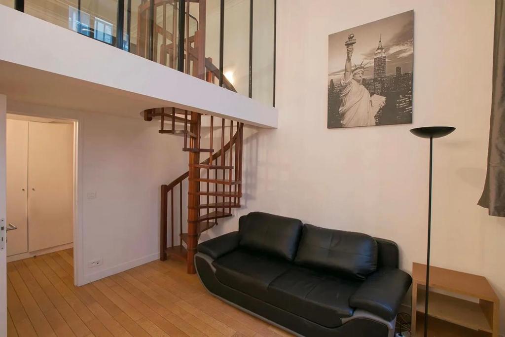 - un fauteuil en cuir noir dans un salon avec un escalier dans l'établissement Love in marais, à Paris