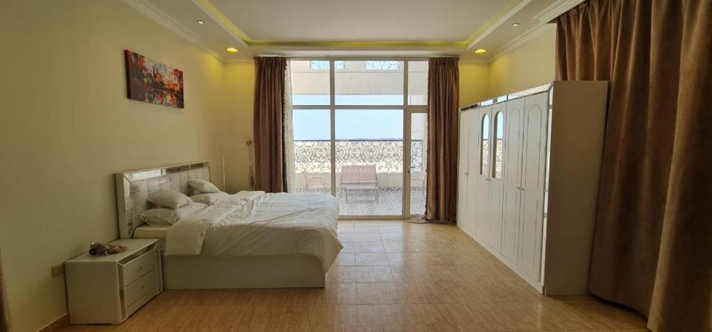 a bedroom with a bed and a large window at كورال بيت العطلات in Al Khobar