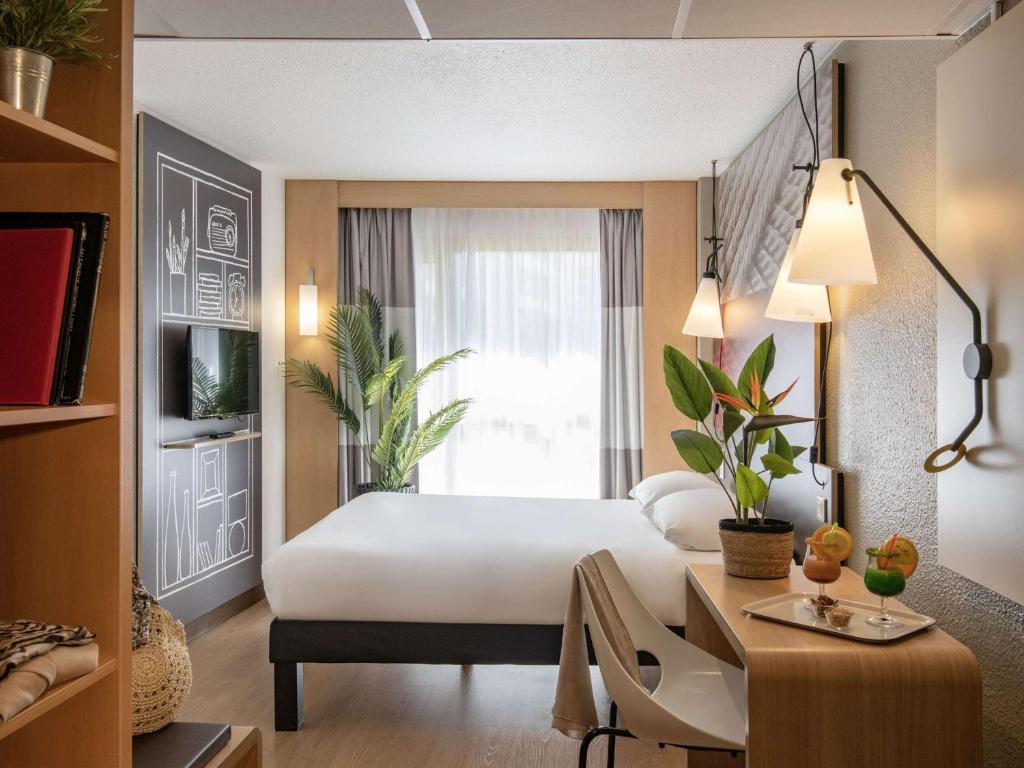 a hotel room with a bed and a desk and a window at ibis Cannes Plage La Bocca in Cannes