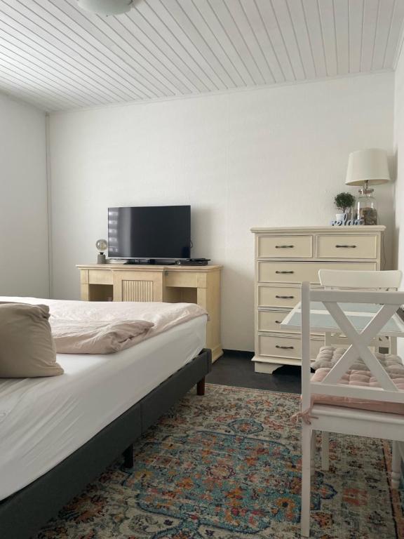 Schlafzimmer mit einem Bett, einem TV und einer Kommode in der Unterkunft Einliegerwohnung in Taunusstein Bleidenstadt in Taunusstein