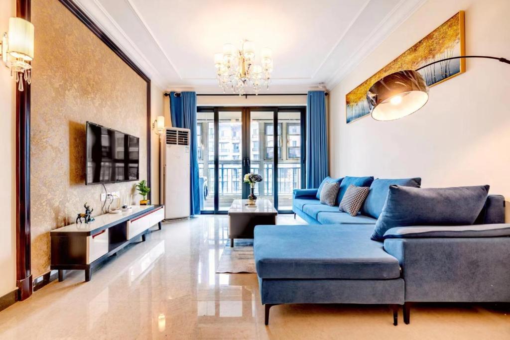 Warm Xian Apartment في شيان: غرفة معيشة مع أريكة زرقاء وطاولة