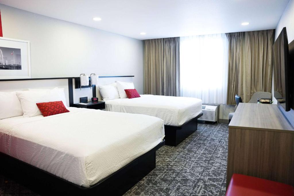 a hotel room with two beds and a desk at Ramada by Wyndham DFW Airport in Irving