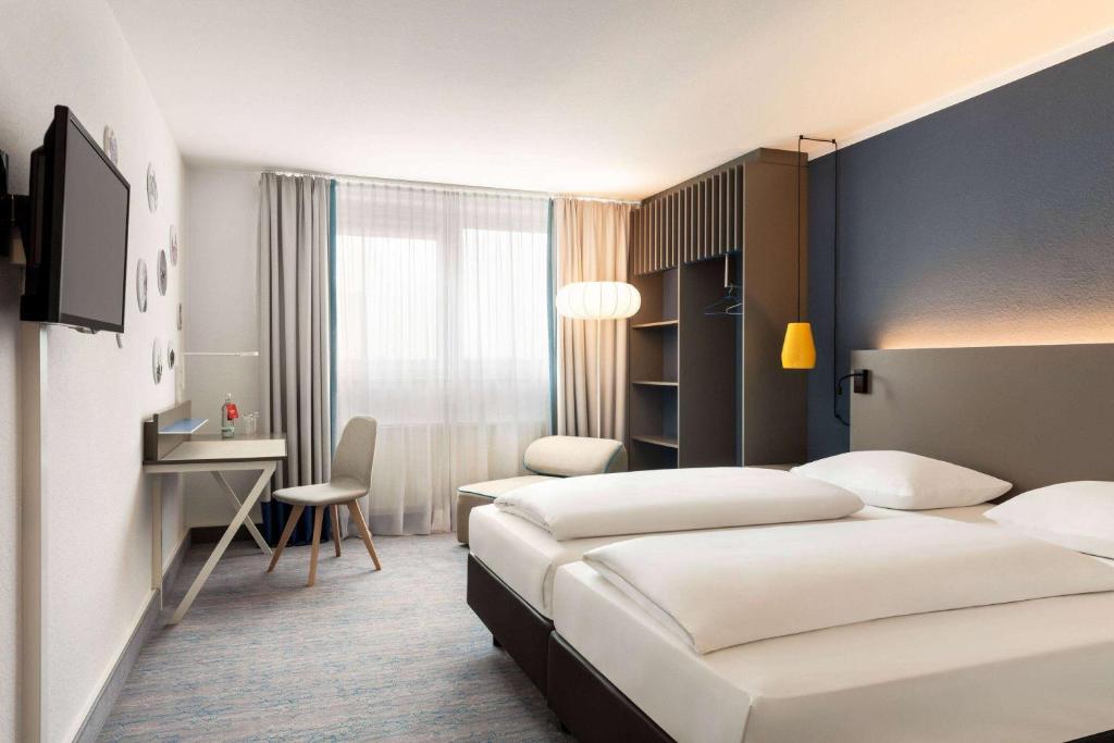 ein Hotelzimmer mit 2 Betten und einem Schreibtisch in der Unterkunft Vienna House Easy by Wyndham Neckarsulm in Neckarsulm