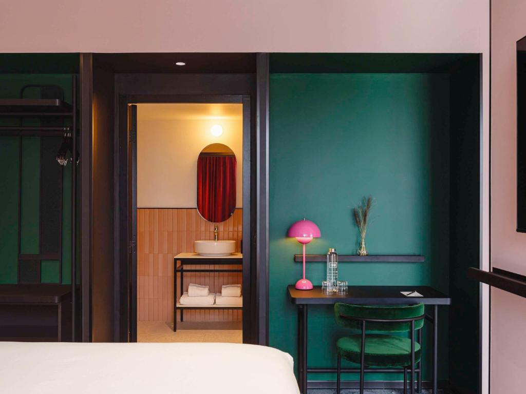 TRIBE Lyon Croix Rousse في ليون: غرفة نوم مع طاولة وجدار أخضر