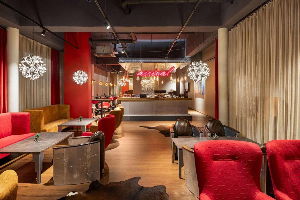 un restaurante con mesas y sillas rojas y un bar en Amedia Express Graz Airport, Trademark Collection by Wyndham en Feldkirchen bei Graz