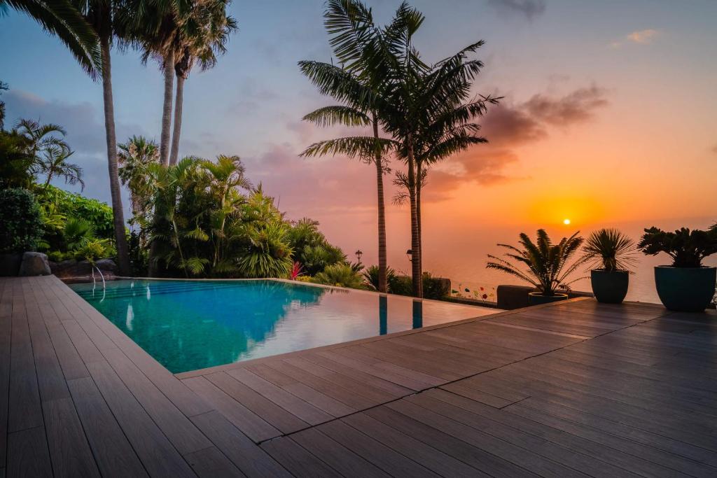 a swimming pool with a sunset in the background at Villa de lujo con piscina y vistas al mar in Tacoronte