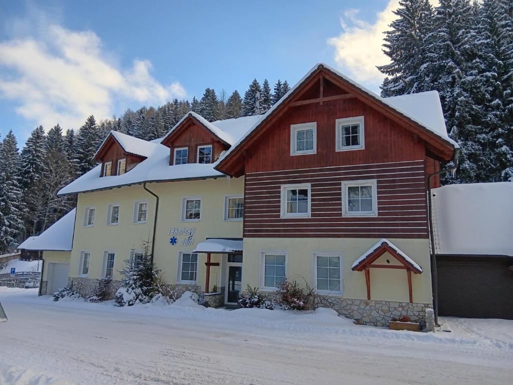 a large house with snow on top of it at Apartmány Lékařský dům in Pec pod Sněžkou