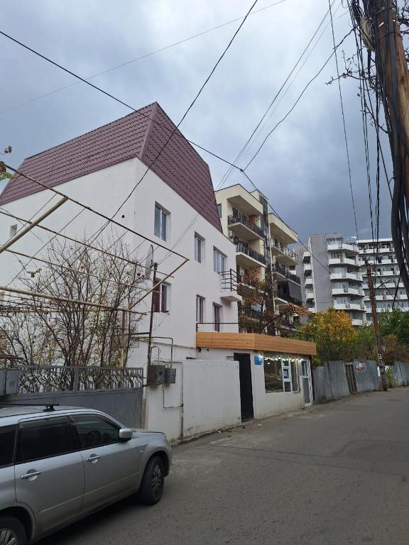 a car parked in front of a white house at vake-house in Tbilisi City