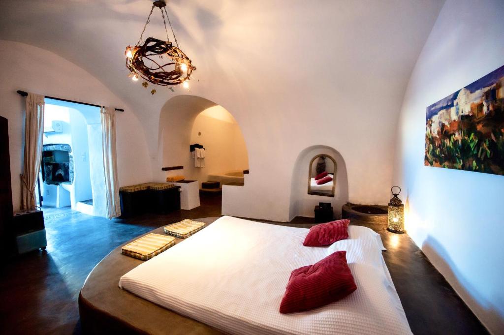 sypialnia z dużym białym łóżkiem z czerwonymi poduszkami w obiekcie Santorini Heritage Villas w mieście Megalochori