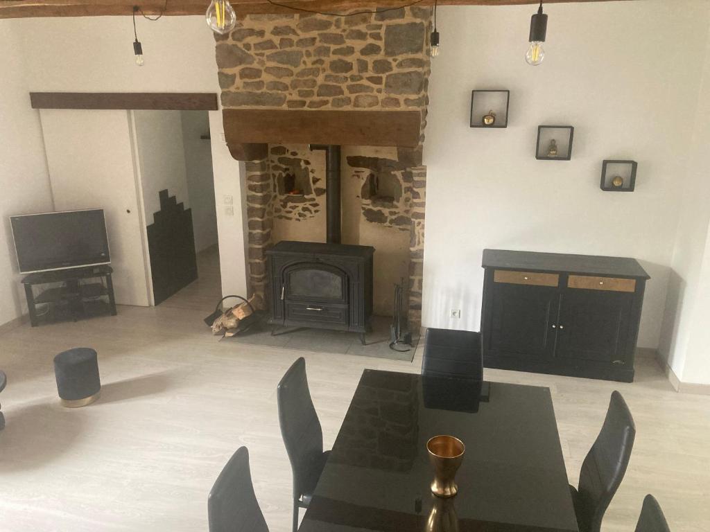 a living room with a fireplace and a table and chairs at Le coetquentellien in Pleudihen-sur-Rance
