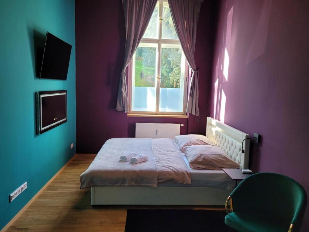 1 dormitorio con 1 cama con paredes de color púrpura y ventana en SPA SPA Apartments Vyšehrad, en Praga