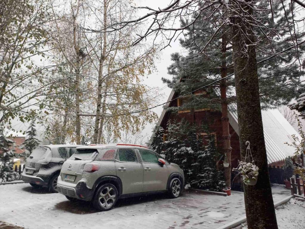 ein Auto, das vor einem Haus im Schnee parkt in der Unterkunft Villa Albani in Peja