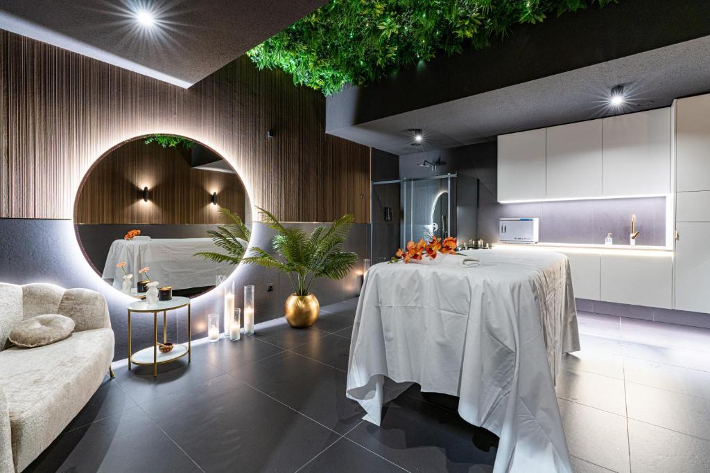 Serene spa room with massage table, large backlit circular mirror, candles and plants.