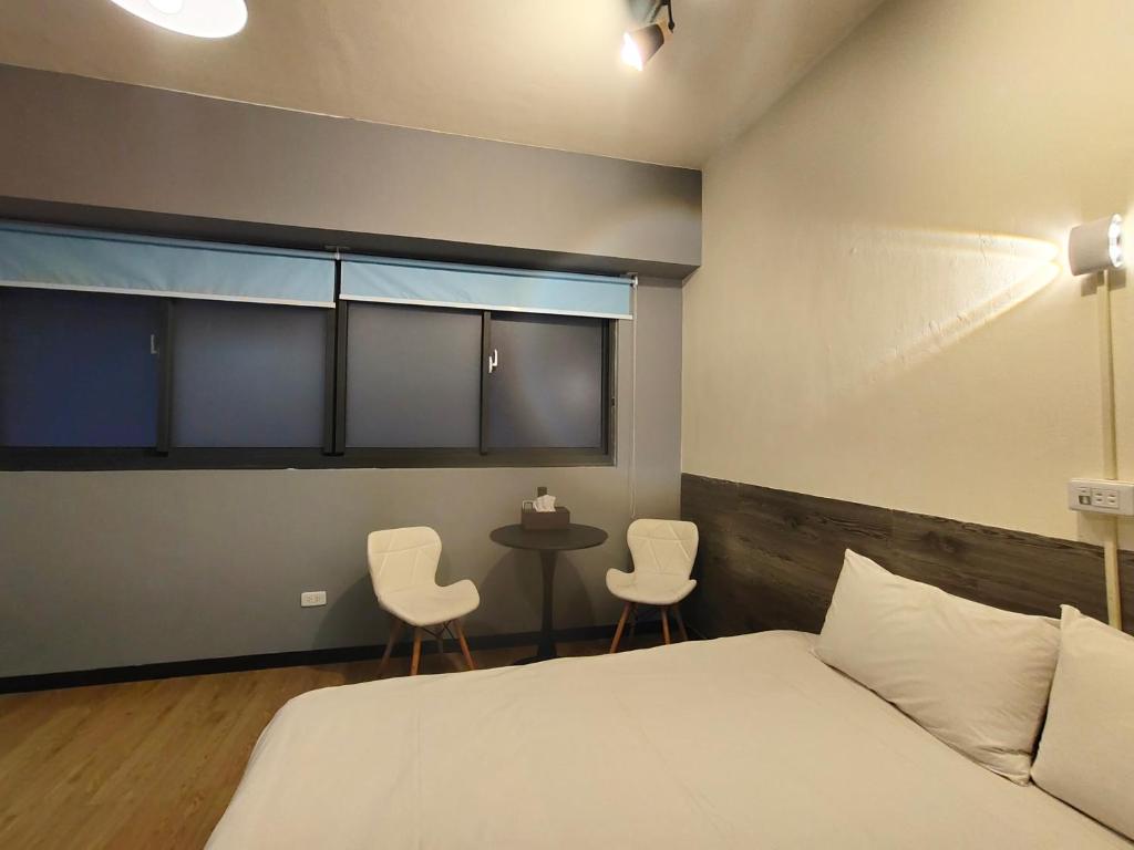 a bedroom with a bed and two chairs and a table at 駐典Txg in Taichung
