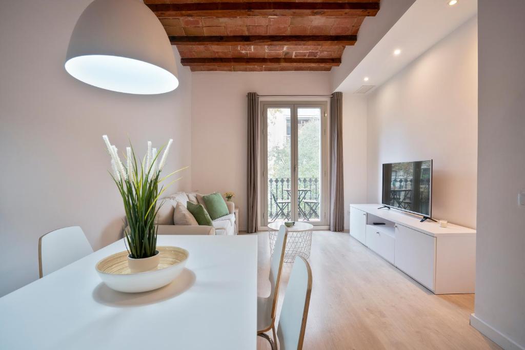 een keuken en een woonkamer met een witte tafel en stoelen bij BcnStop Sant Pau Suites in Barcelona