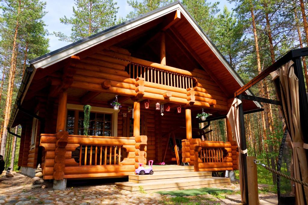 a log cabin with a deck in the woods at Kettu Holl Cottage in Taipalsaari
