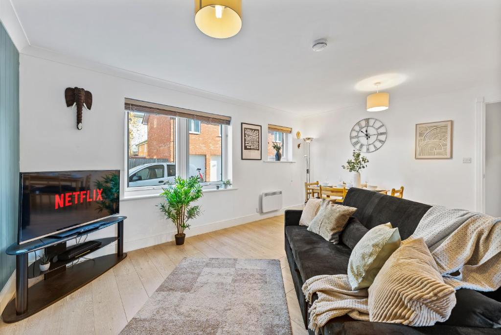 uma sala de estar com um sofá preto e uma televisão em Beautiful 2 Bed Apartment in Warwick - Parking em Leek Wootton