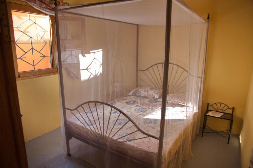 a bedroom with a canopy bed with a window at Auberge Plein Soleil in Mbodiène