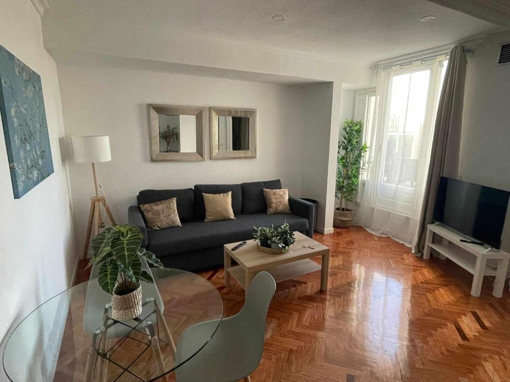 uma sala de estar com um sofá e uma mesa de vidro em Apartamento con terraza y vistas AlcaláRetiro em Madri