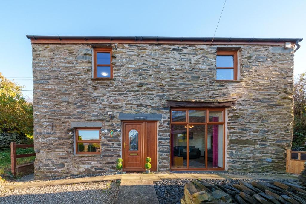 un cottage in pietra con una porta e finestre in legno di Farm Cottage - Kirkby-In-Furness, ideal for the Central Lake District a Soutergate