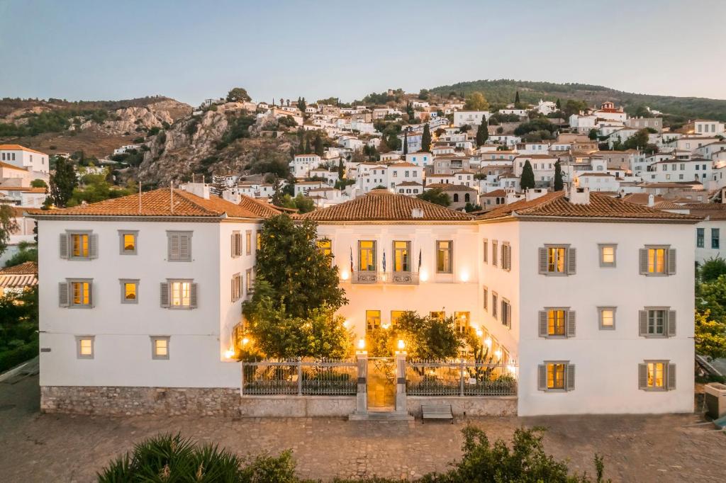 a large white building with a city in the background at Hydroussa Hotel Hydra in Hydra