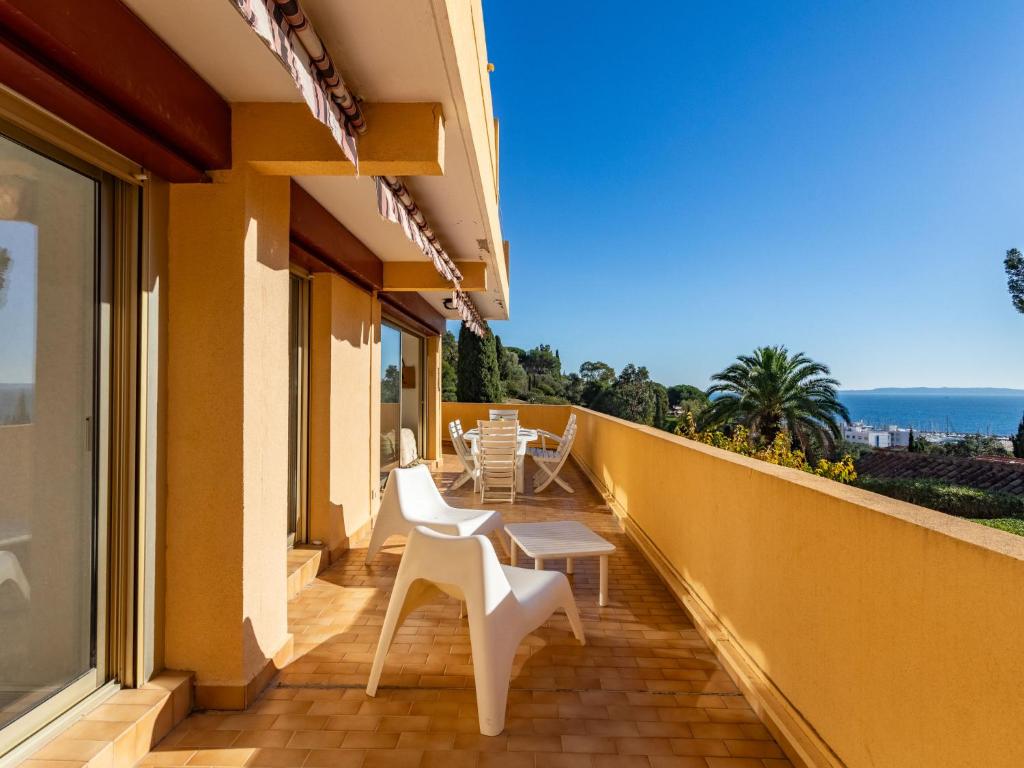 a balcony with white chairs and a view of the ocean at Apartment Cadet Rousse-6 by Interhome in Le Lavandou