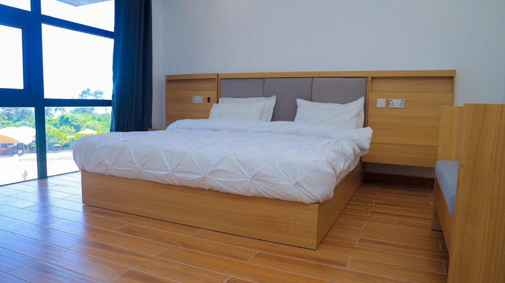 a bedroom with a large bed with a wooden headboard at PALM VILLAGE BUSINESS HOTEL in Dar es Salaam