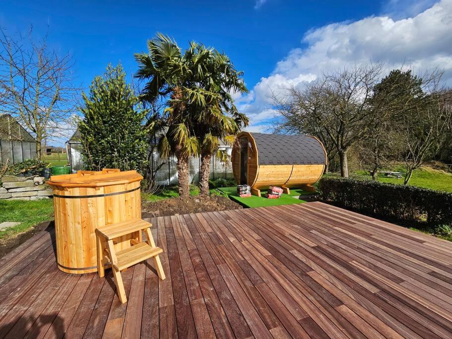 eine Holzterrasse mit einem Mülleimer und einem Stuhl in der Unterkunft BNB Green refuge: Vakantiehuis met zeer grote tuin in Londerzeel