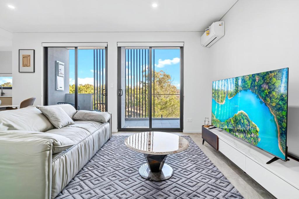 a living room with a couch and a tv at Urban Oasis in Heart of Homebush in Sydney