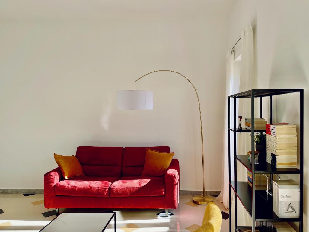 um sofá vermelho numa sala de estar com um candeeiro em The Design Pasta Apartment em Roma