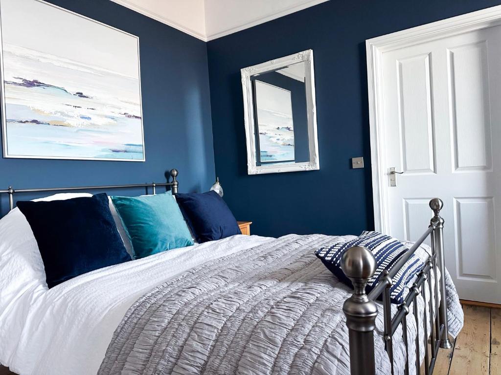 um quarto com uma cama com paredes azuis em View at 142 em The Mumbles