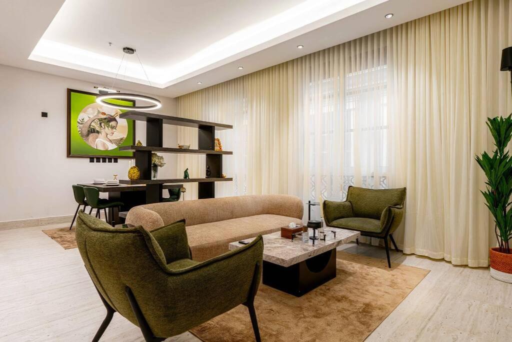 ein Wohnzimmer mit einem Sofa, Stühlen und einem Tisch in der Unterkunft Nuzul R154 - Elegant Apartment in Riad