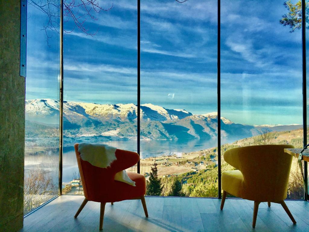 two chairs in front of a large window with snow covered mountains at Engeset Trehytter in Vereide