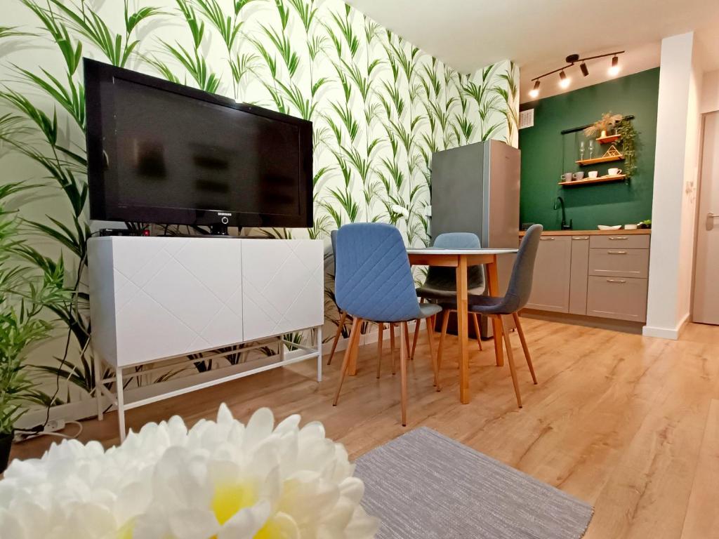 een woonkamer met een tv en een tafel en stoelen bij Holi Resort in Serock