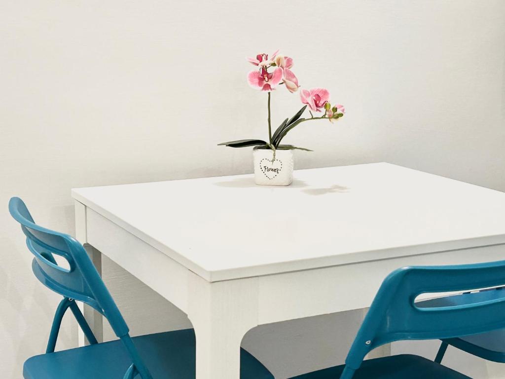 Una mesa blanca con un jarrón con flores rosas. en Residence Annunziata, en Gaeta