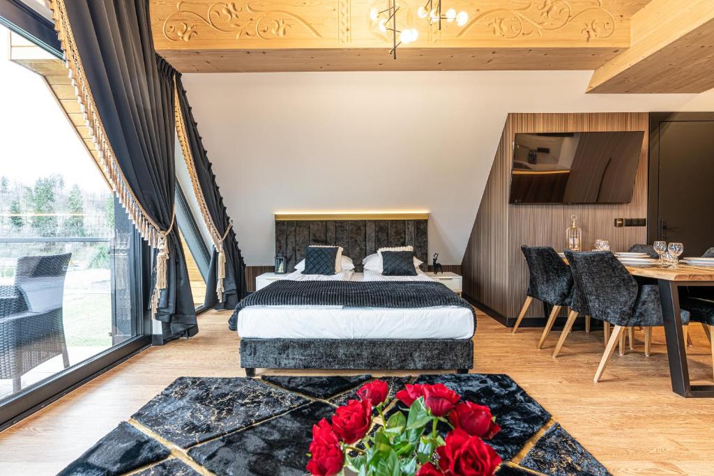 Bedroom with low bed, decorative curtains, balcony access and black rug with red roses in foreground