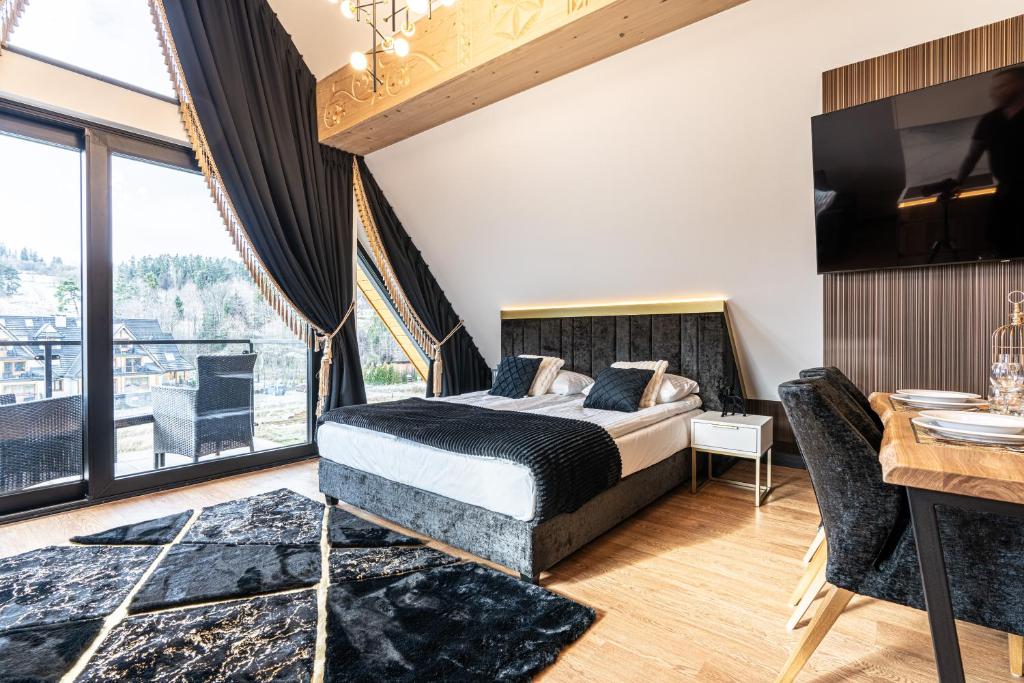 Contemporary bedroom with balcony doors, plush bed, black curtains and patterned rug.