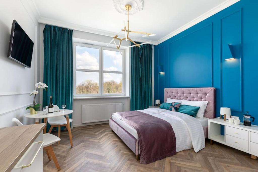 sypialnia z niebieskimi ścianami, łóżkiem i stołem w obiekcie Rent like home - Gagarina 33 w Warszawie