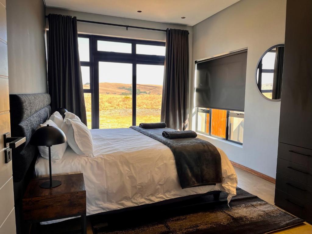a bedroom with a bed and a large window at Highland Gate Range View in Dullstroom