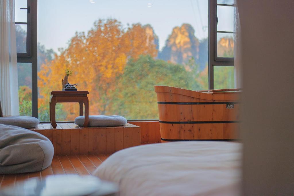 um quarto com uma cama e uma grande janela em Mount View Cottage em Zhangjiajie