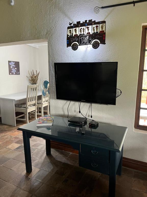 a living room with a table and a tv on a wall at Mi Casita in Graskop