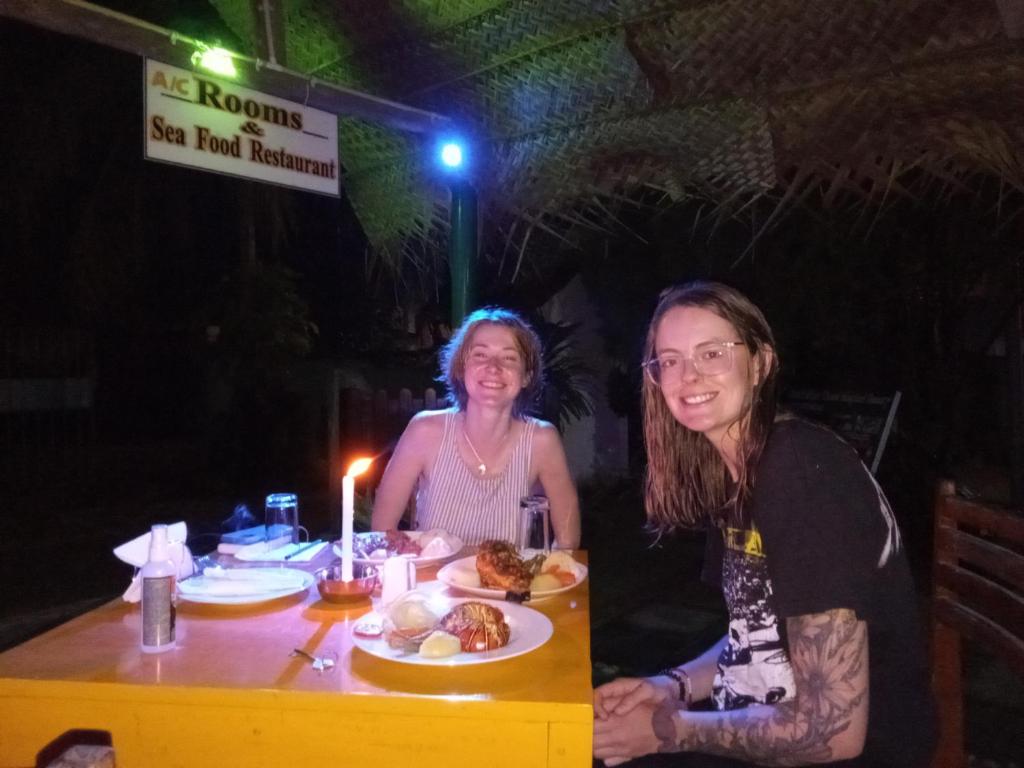dos mujeres sentadas en una mesa con un plato de comida en Viraj's Garden, en Tangalle