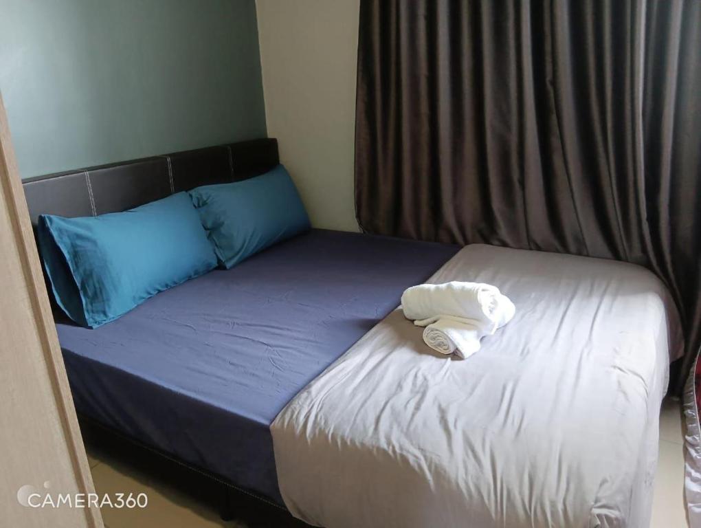 a bed with two pillows and a towel on it at Bayan Lepas Cozy Family Stay Sea & Airport View in Kampong Batu Maung