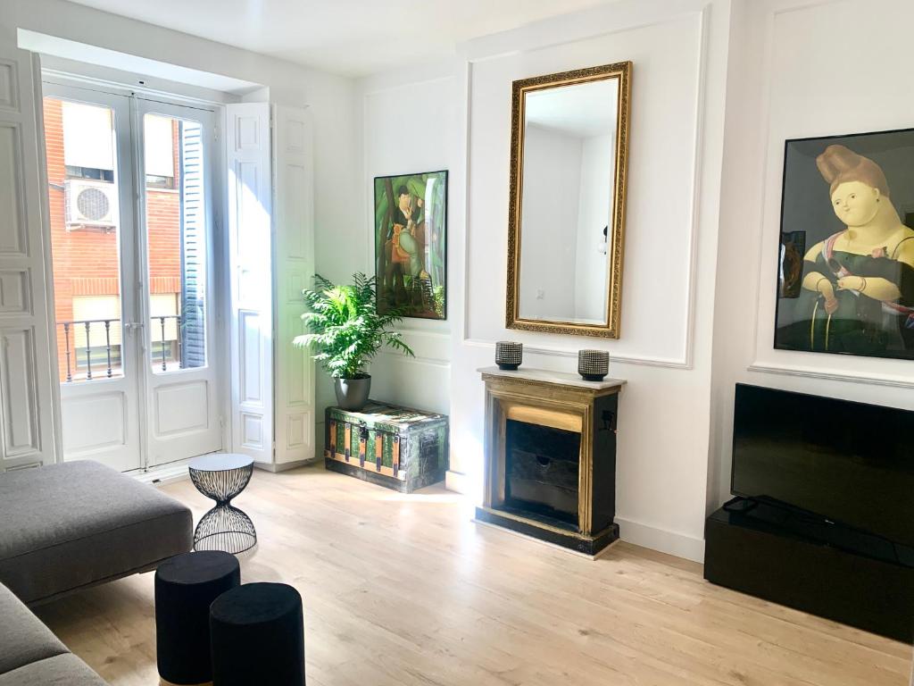 a living room with a fireplace and a mirror at Piso recien reformado, junto a Gran Via in Madrid