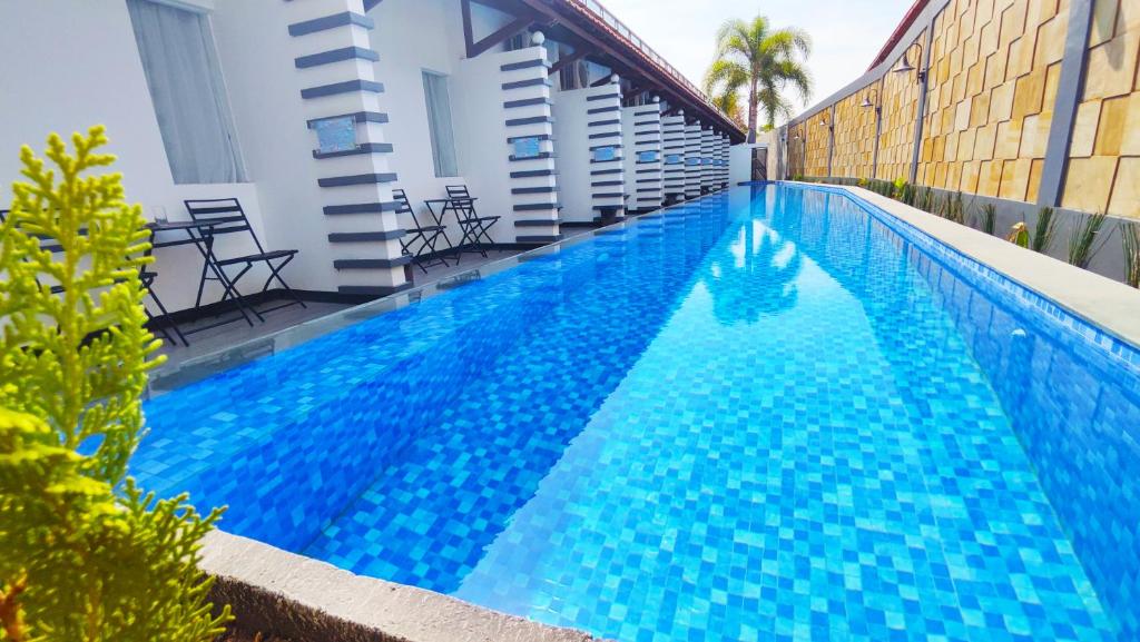 Pademabu的住宿－Odaita Hotel Pamekasan Madura，一座大型蓝色游泳池,位于大楼旁边