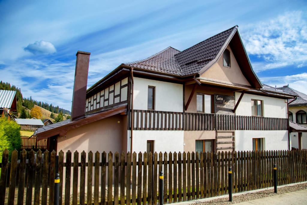 a house with a wooden fence in front of it at Casa Lulu in Dorna Cîndrenilor