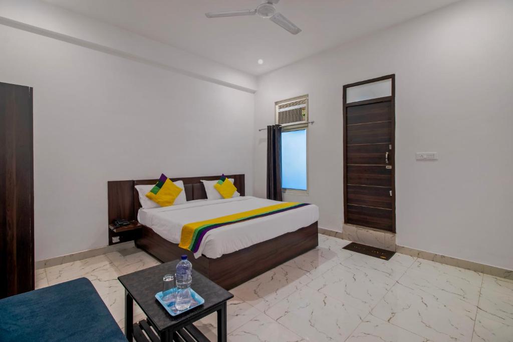 a bedroom with a king sized bed and a table at Itsy By Treebo - Om Pushp Residency in Mathura