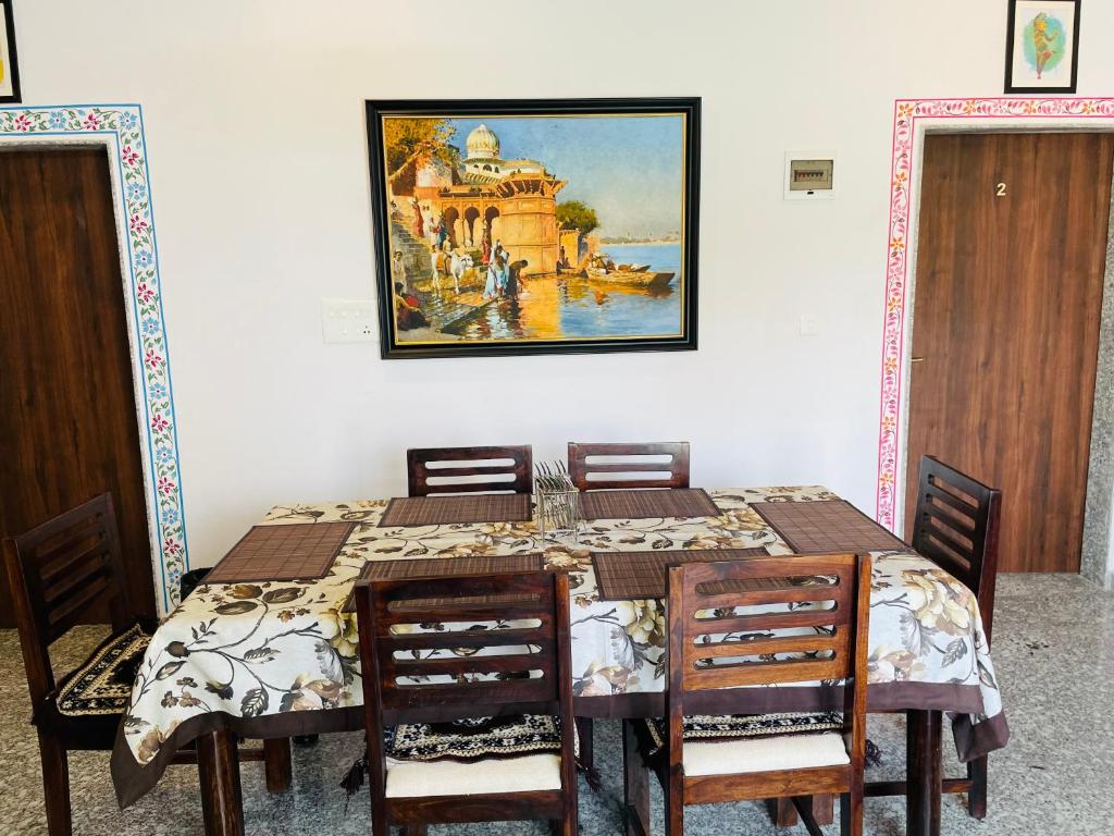 a dining room table with chairs and a painting on the wall at Krishna kottage A Boutique Home Stay in Udaipur
