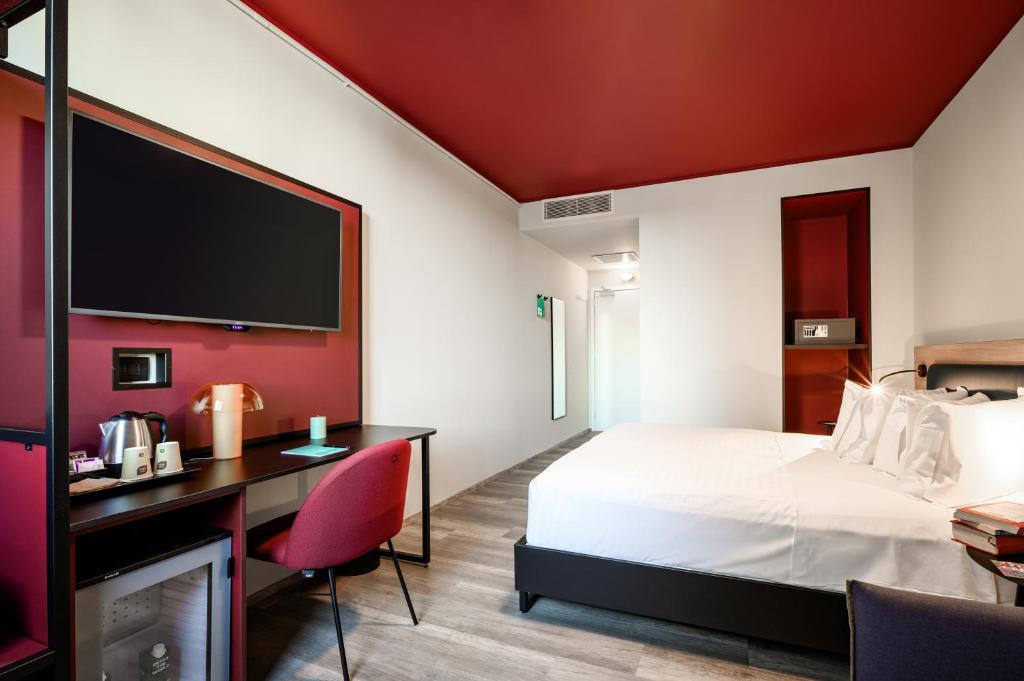 a hotel room with a bed and a desk and a tv at CX Venice Mestre in Mestre